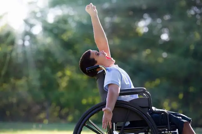 Boy in wheelchair cheering at the sky